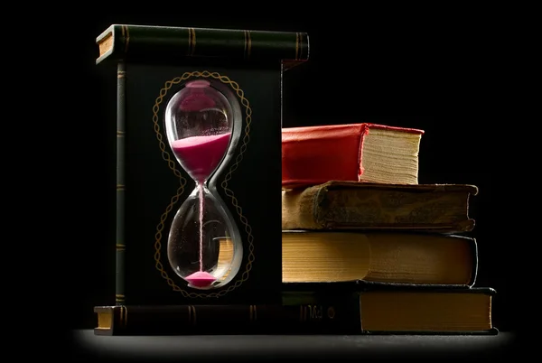 Stock image A pile of old books and sand glass