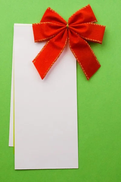 Red bow with card on green — Stock Photo, Image