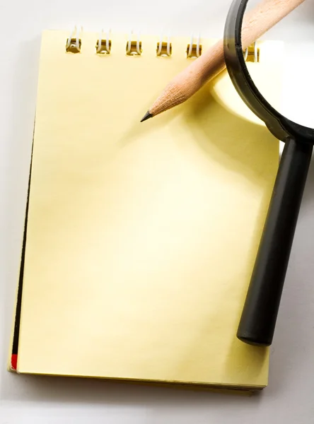 Notepad, pencil and magnifying glass — Stock Photo, Image