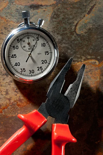 Stopwatch and pliers on the rusty plate — Stock Photo, Image