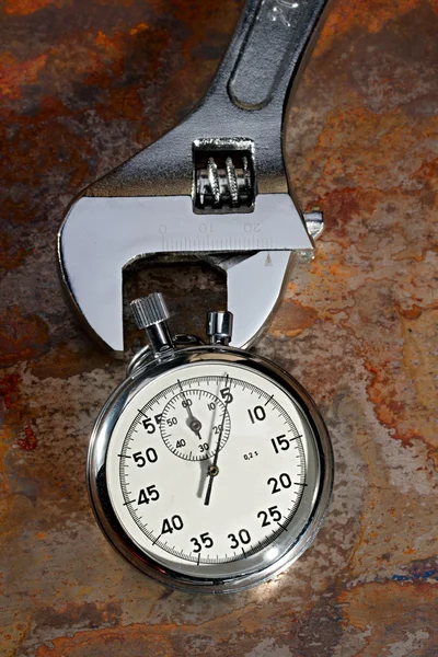 Spanner y cronómetro en el plato oxidado — Foto de Stock