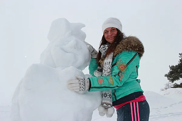 Dark-haired woman in the winter with snowman — Stock Photo, Image