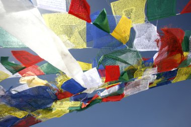 Praying flags floating in the wind on blue sky clipart
