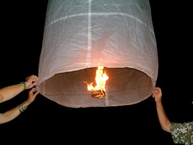 Fire lanterns taking off on the beach in Thailand. clipart