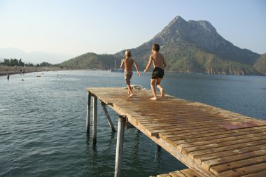 Kids running and jumping from pier clipart