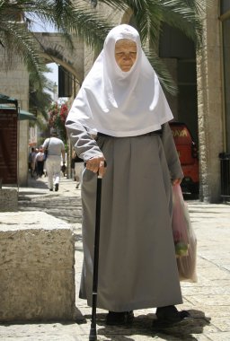 Old nun in jerusalem with her groceries and walking stick clipart