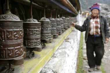Old man spining praying wheel, annapurna, nepal clipart