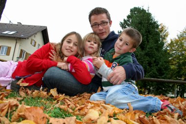 Father holding his children in his arm in a park