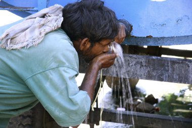 Man drinking water from tank, south india clipart