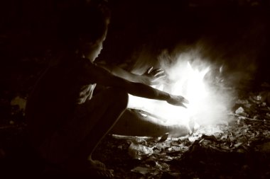 Poor street kid heating herself with fire, nepal clipart