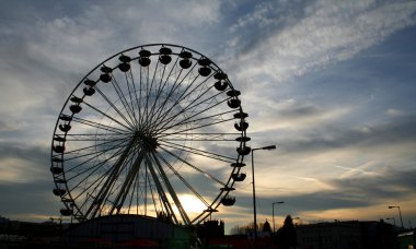 Ferris wheel silhouette on cloudy sky clipart