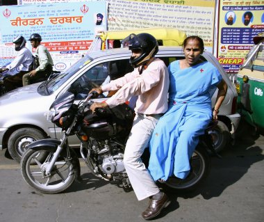 Couple on motorcycle in traffic, delhi, india clipart