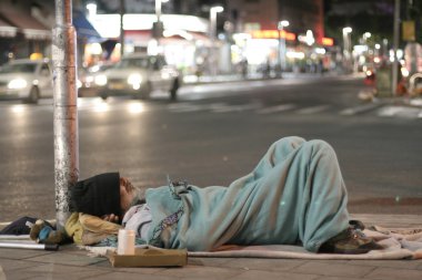 Male homeless sleeping in a street clipart