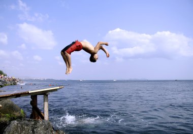 Young man doing a back flip into sea, istanbul clipart