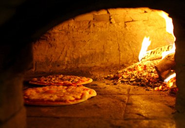 Pizzas baking in an open firewood oven clipart