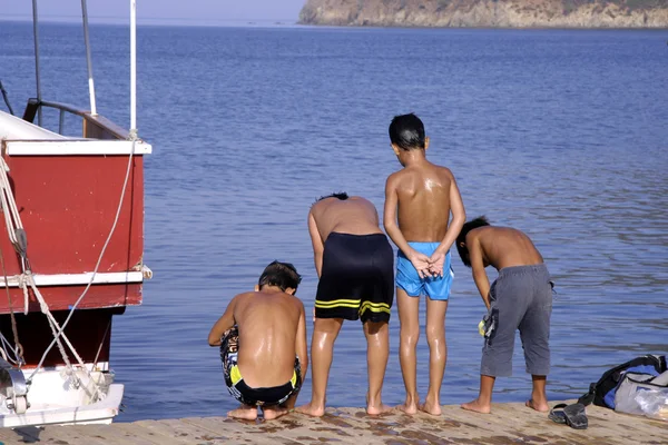Młodzi chłopcy na molo, patrząc na przyjaciela w morze — Zdjęcie stockowe