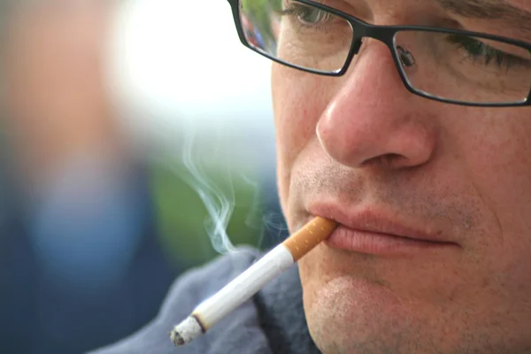 Мужчина в очках курит сигарету — стоковое фото