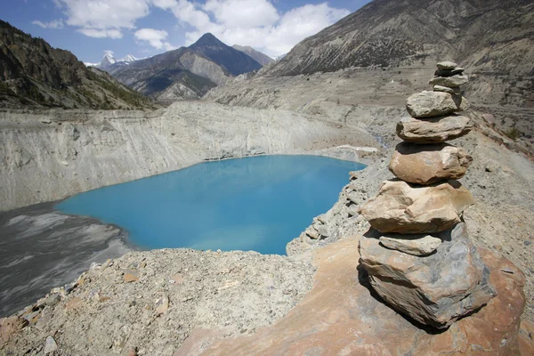 Memorial stones piled infront of blue mountain lake, annapurna, nepal — Stock Photo, Image