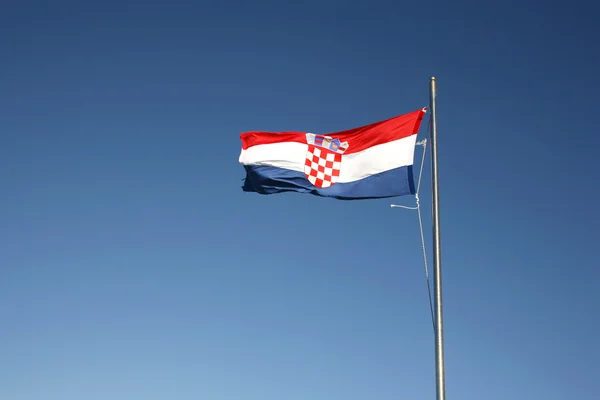 :Bandeira croata flutuando em um céu azul — Fotografia de Stock