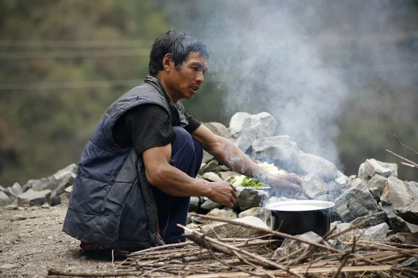 Man preparing food in a pot with fire wood, annapurna, nepal — Stock Photo, Image
