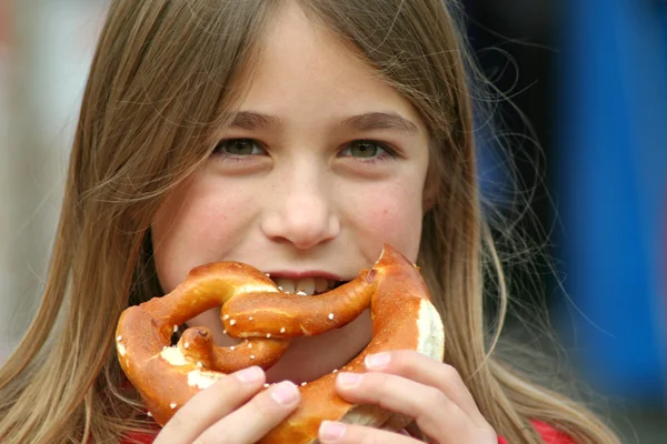 年轻的女孩吃 brezel 面包 — 图库照片