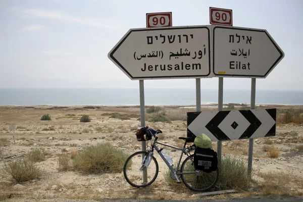 Fiets geparkeerd tegen de verkeerstekens Jeruzalem en eilat — Stockfoto
