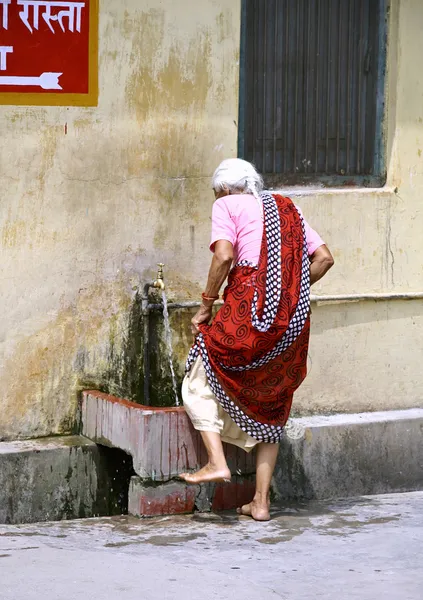 Oude dame wassen haar voeten, rishikesh, india — Stockfoto