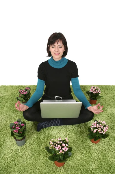 Donna seduta sull'erba con fiori intorno meditando con un computer portatile — Foto Stock
