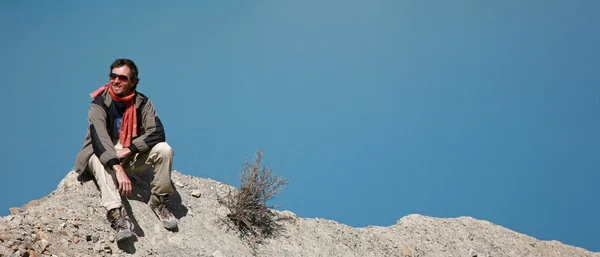 Wanderer sitzt auf Berggipfel mit blauem See im Hintergrund — Stockfoto