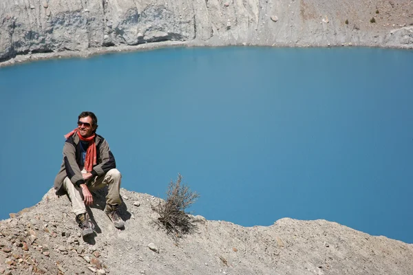 Wanderer sitzt auf Berggipfel mit blauem See im Hintergrund — Stockfoto