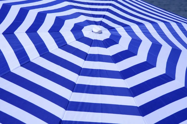 Blue and white striped parasol on beach — Stock Photo, Image