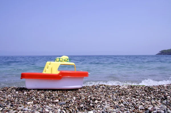 Barca di plastica giocattolo rosso e giallo sulla spiaggia — Foto Stock