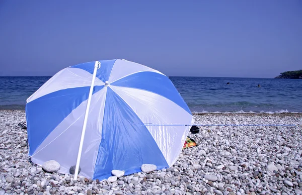 Blau-weiß gestreifter Sonnenschirm am Strand — Stockfoto