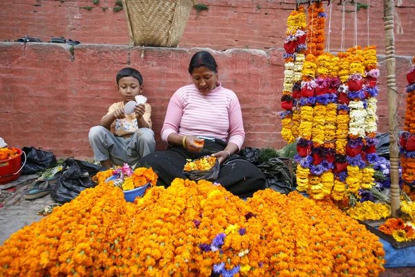 Lady and her son selling marigold necklaces on durbar square, kathmandu, ne — Stock Photo, Image