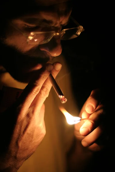 Человек курит сигарету в темноте — стоковое фото