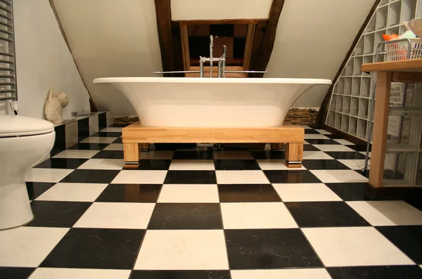 Горизонтальный вид на ванну на черно-белом полу плитки — стоковое фото