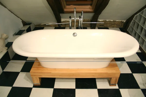 Blick auf die Badewanne auf einem schwarz-weißen Fliesenboden — Stockfoto