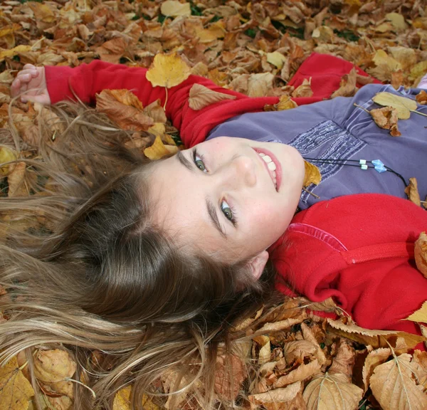 Jovem deitada em folhas de outono — Fotografia de Stock