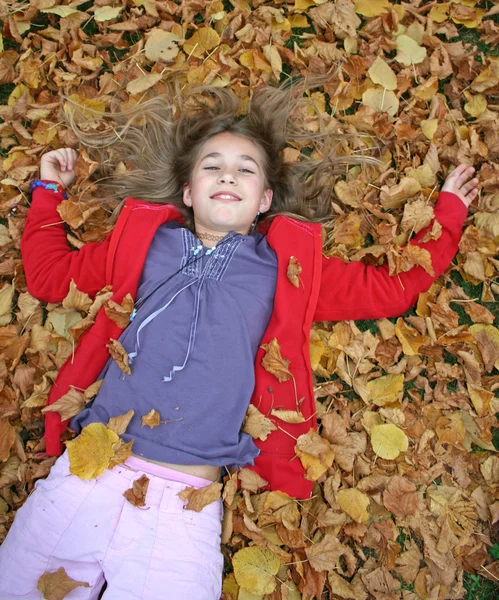 Mladá dívka leží v podzimní listí — Stock fotografie