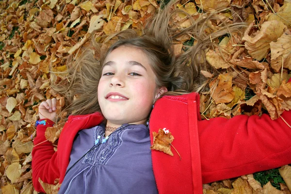 Close up jovem com cabelo em folhas de outono — Fotografia de Stock