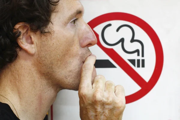 Άνθρωπος που καπνίζει μια πινακίδα μη καπνιζόντων — Φωτογραφία Αρχείου