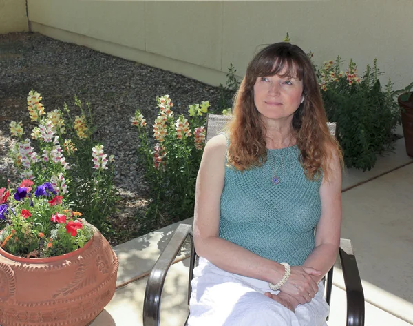一个女人坐在露台花园的花儿之间 — 图库照片