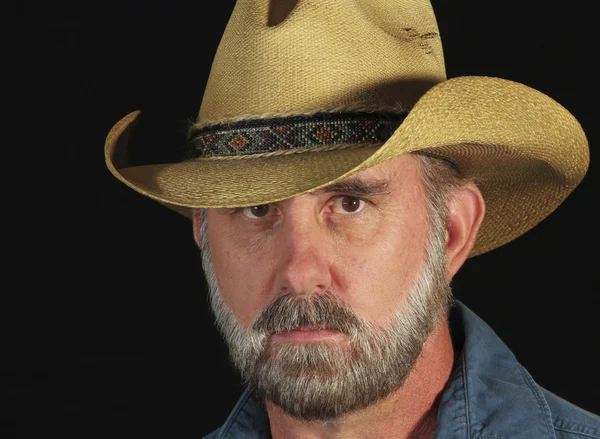 Un bărbat cu barbă gri într-o pălărie de cowboy de paie — Fotografie, imagine de stoc