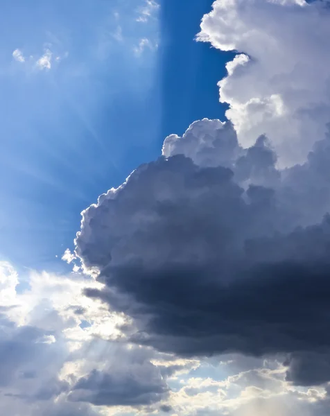 Um céu azul cheio de nuvens e raios de sol — Fotografia de Stock