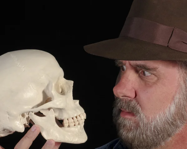 Un hombre en un Fedora examina un cráneo — Foto de Stock