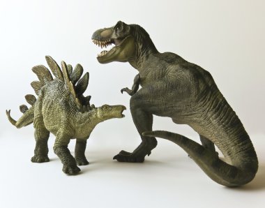 A Stegosaurus and Tyrannosaurus Against a White Background clipart