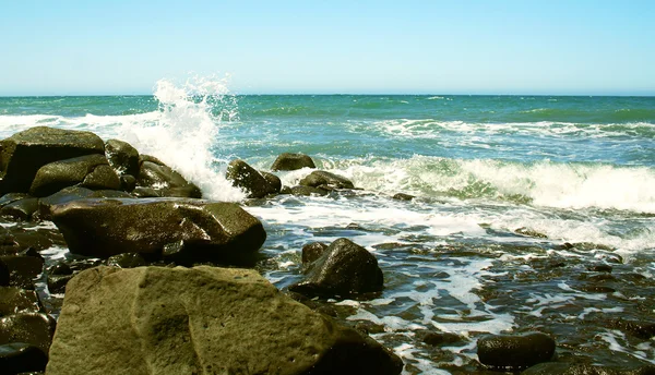 Golven breken op de rotsachtige kust van een blauw-groene zee — Stockfoto