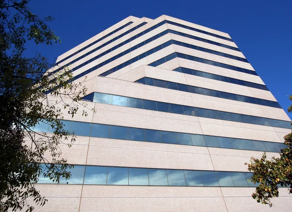 En hög kontorsbyggnad återspeglar moln — Stockfoto