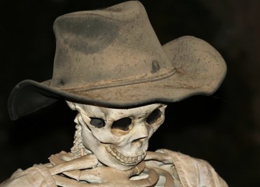 A Skeleton in a Cowboy Hat Against Black clipart