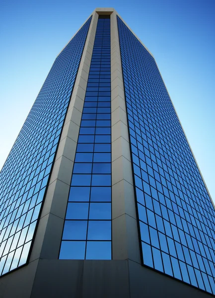 Une tour en verre solitaire reflète le bleu ciel — Photo